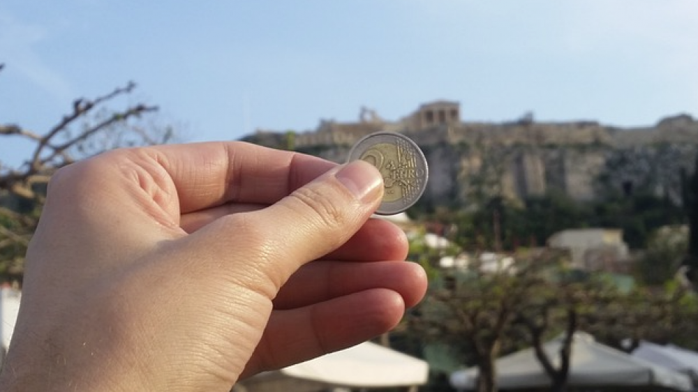 Ein Zwei-Euro-Stück vor der griechischen Akropolis (Symbolbild). Die europäische Standard-Privatrente soll überall in der EU in Anspruch genommen werden können.