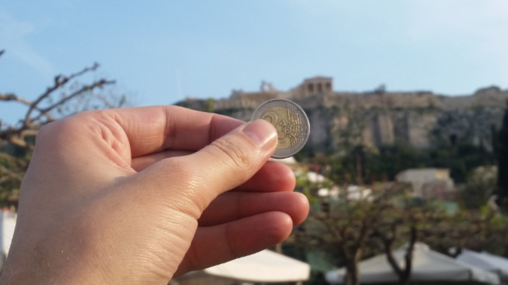 Euromünze vor griechischer Kulisse: Das Aufsichtsregime Solvency II erfasse nur unzureichend Ausfallrisiken von Staatsanleihen, kritisiert die BaFin (Symbolbild).