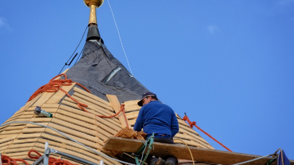 Gefährliche Arbeit: ein Dachdecker arbeitet in schwindelerregenden Höhen. Eine BU-Versicherung empfiehlt sich zur Absicherung der Arbeitskraft (Symbolbild).