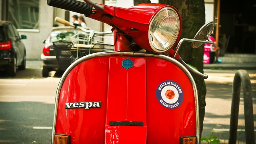 Eine Vespa auf einem innerstädtischen Parkplatz (Symbolbild). Ab März brauchen Mopeds neue Kennzeichen.